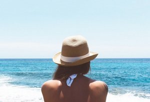 Woman wearing a straw sun hat looking out across the sea